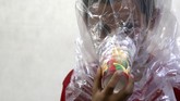 Tak mau kepanikan itu terulang, mereka bersiap. Seorang ayah terlihat menempelkan gelas kertas warna-warni berisi kapas dan arang ke wajah anaknya, kemudian membungkus kepala bocah itu dengan kantung plastik. (Reuters/Khalil Ashawi)