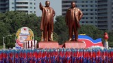 Orang-orang membawa bendera di depan patung pendiri Korea Utara Kim Il Sung (Kiri) dan mendiang pemimpin Kim Jong Il selama parade militer menandai peringatan 70 tahun pendirian Korea Utara di Pyongyang. (REUTERS/Danish Siddiqui)