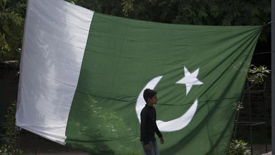 A boy walks past a Pakistani flag displayed for sale ahead of Pakistan's Independence Day, along a road in Rawalpindi August 12, 2012. Pakistan commemorates its Independence Day on August 14. REUTERS/Faisal Mahmood  (PAKISTAN - Tags: SOCIETY ANNIVERSARY POLITICS) - RTR36QOE