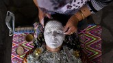 Kosovar Sheqerie Buqaj tengah berbaring sembari seorang wanita yang dituakan merias wajahnya. Buqaj memutuskan menikah dengan riasan tradisional Bonsia. (AFP PHOTO / Armend NIMANI)