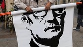 Seorang pria menggulung gambar wajah mendiang presiden Chile, Salvador Allende, saat peringatan 45 tahun kudeta militer 1973 di Santiago, Chili. (REUTERS/Ivan Alvarado)