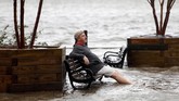 Seorang pria duduk di bangku taman yang dipenuhi air banjir. Badai Florence membuat air sungai Cape Fear di Wilmington meluap hingga ke taman-taman. (REUTERS/Jonathan Drake)