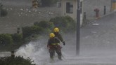 Pemadam kebakaran mencoba bertahan saat ombak tinggi menghantam pantai di Heng Fa Chuen, sebuah distrik penduduk di dekat pantai di Hong Kong. (REUTERS/Bobby Yip)