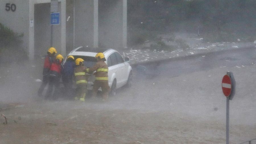 Firefighters push a car in flooded waters as high waves hit the shore at Heng Fa Chuen, a residental district near the waterfront, as Typhoon Mangkhut slams Hong Kong, China September 16, 2018. REUTERS/Bobby Yip