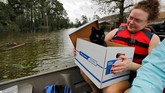 Saat melihat peliharaan yang panik, mereka langsung menghampiri, berupaya menenangkan, kemudian memasukkan peliharaan itu ke dalam perahu. (Reuters/Jonathan Drake)
