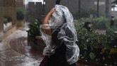 Seorang pejalan kaki menggunakan ponco plastik ketika terjadinya Topan Super Mangkhut di Hong Kong. Dalam perjalanannya menuju China dari Filipina, Mangkhut sempat menewaskan 30 orang di Filipina dan menghancurkan area pertanian, juga membuat gedung-gedung tinggi bergoyang. (AFP/Anthony Wallace)
