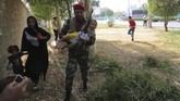 Suasana seketika kacau balau. Para tentara merangkak sembari mencari sumber tembakan, sementara perempuan dan anak-anak berlarian menyelamatkan diri mereka. (AFP Photo/Mehdi Pedramkhou)