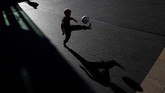 Jelang penghargaan Pemain Terbaik Dunia FIFA, seorang bocah bermain sepak bola di luar Royal Festival Hall di London. (AFP PHOTO / Adrian DENNIS)