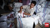 Pak Sakun, pemilik usaha sablon mengemas kaos ke dalam karung untuk dikirim ke pemesan di Sulawesi Utara. Menurutnya, sudah ada pesanan baru lagi dari berbagai partai dan perseorangan yang harus mereka kerjakan dalam waktu yang cepat. (CNNIndonesia/Safir Makki)