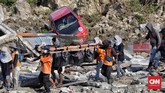 Tim Basarnas bersama warga mengevakuasi beberapa korban gempa yang masih terjebak reruntuhan puing bangunan di Balaroa. Banyak korban yang terjebak di kubangan dan reruntuhan sehingga sukar dievakuasi. (CNN Indonesia/Adhi Wicaksono)