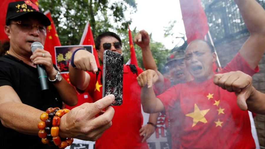 Perang dagang Amerika Serikat dan China memicu protes dan pembakaran iPhone di depan kedutaan AS di Hong Kong.