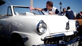Seseorang membersihkan kaca depan mobil Studebaker cabriolet dalam parade Place de la Concorde yang merupakan bagian dari pameran otomotif Paris Motor Show ke-120 di Paris, Prancis. (REUTERS/Benoit Tessier)