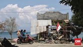 Tiga orang warga berboncengan di atas sebuah sepeda motor saat melintasi sebuah rumah warga yang hancur akibat terjangan tsunami di Desa Loli Pesua, Donggala, Sulawesi Tengah, 3 Oktober 2018. (CNNIndonesia/Adhi Wicaksono)