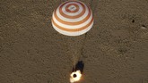 Turun menggunakan parasut oranye dan putih yang mengepul. Parasut ini touchdown dibantu roket di Dzhezkazgan, Kazakhstan. (Maxim Shipenkov/Pool via REUTERS)
