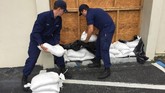 Penjaga pantai mempersiapkan kantong pasir di depan pintu masuk stasiun pemadam kebakaran di Yankeetown, Florida (U.S. Coast Guard/Seaman Michael Clark/Handout via REUTERS)