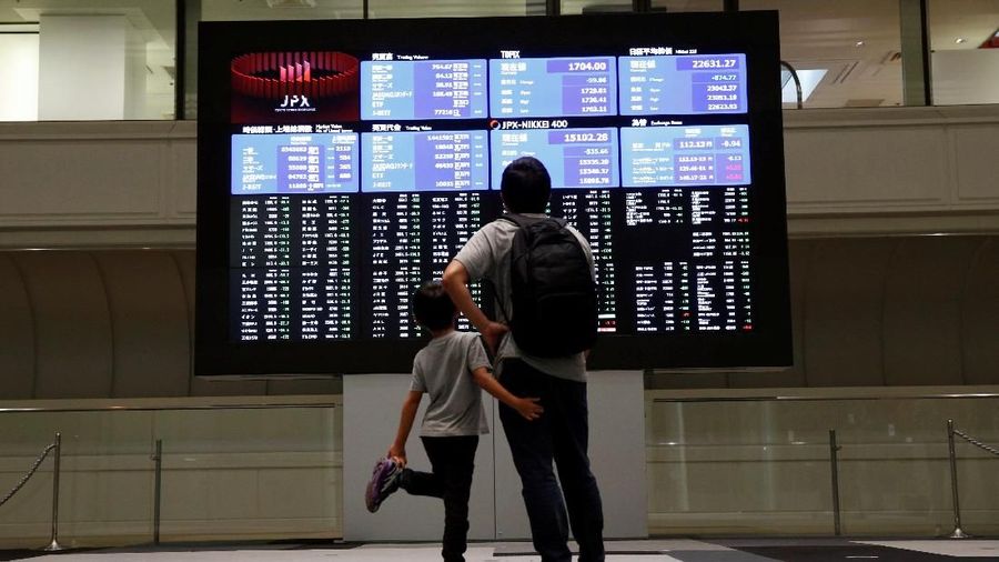 A passerby walks past an electronic board displaying a graph showing recent movement of Japan's Nikkei average outside a brokerage in Tokyo, Japan, October 11, 2018. REUTERS/Issei Kato
