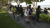 Tamu asing mengendarai sepeda melewati para petugas keamanan wilayah laut dekat dengan lokasi Pertemuan Tahunan IMF-World Bank 2018. (AFP PHOTO/SONNY TUMBELAKA).
