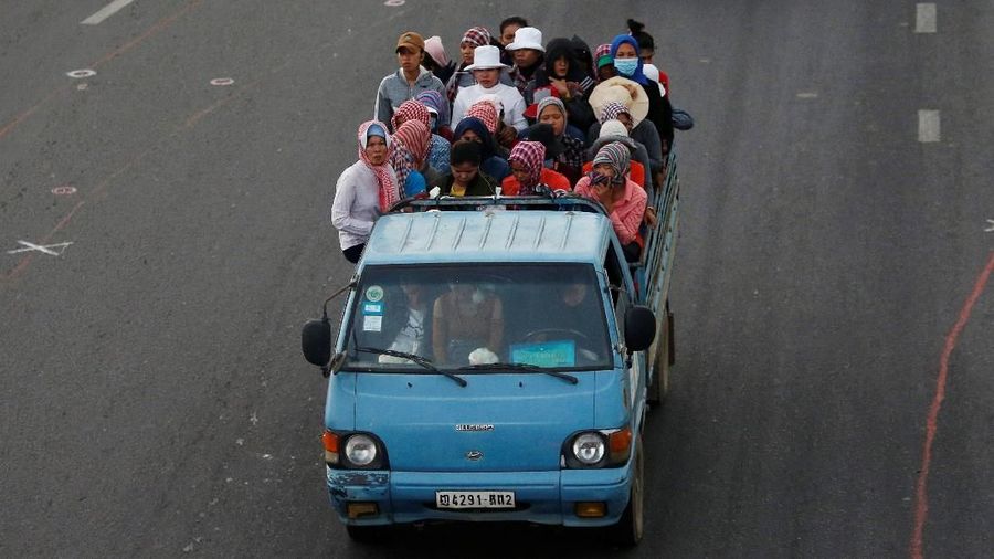 Garment workers stand on the back of a truck as they travel to work, on the outskirts of Phnom Penh, Cambodia, October 17, 2018. REUTERS/Samrang Pring