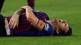Lionel Messi memegang tangan kanan dan mengerang kesakitan setelah terjatuh usai berduel dengan pemain Sevilla Franco Vazquez. (REUTERS/Albert Gea)