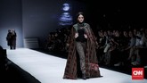 Kebaya pun dijodohkan dengan tenun. Kebaya kutu baru berwarna hijau plus bagian garis tengah tubuh berwarna merah, dipadukan dengan bawahan tenun hijau. Tak lupa ia menyematkan kerudung dengan warna senada. (CNNIndonesia/Safir Makki)
