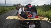 Masih belum diketahui berapa total korban akibat badai ini. Seorang anak kecil yang terluka tengah diantar orang tuanya dengan motor dari kampung nelayan yang aksesnya masih tertutup (Photo by Alfredo ESTRELLA / AFP)