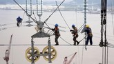 Para pekerja berada di atas kabel listrik yang menghubungkan menara transmisi di Zhoushan, Provinsi Zheijang, China. (REUTERS/Stringer)
