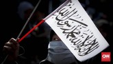 Dalam aksi ini, massa membawa bendera berwarna hitam dan putih yang diyakni sebagai panji rasul yang memuat kalimat tauhid. (CNNIndonesia/Safir Makki)