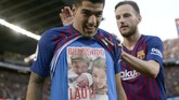 Luis Suarez menunjukkan foto anak ketiganya yang baru lahir sebagai pertanda gol tersebut ia persembahkan kepada sang anak. (Photo by Josep LAGO / AFP)