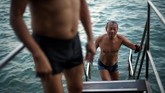 Mereka telah berenang di sana selama beberapa dekade. Mereka terjun ke air laut dari sebuah jembatan kecil dengan latar belakang kapal-kapal kontainer yang sibuk, deretan kapal feri lalu lalang, dan berbagai kapal nelayan. (REUTERS/Hannah McKay)