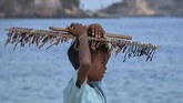 Bocah pedagang asongan berada di pinggir pantai Kawasan Ekonomi Khusus Mandalika di Desa Kuta, Kecamatan Pujut, Praya, Lombok Tengah, NTB.