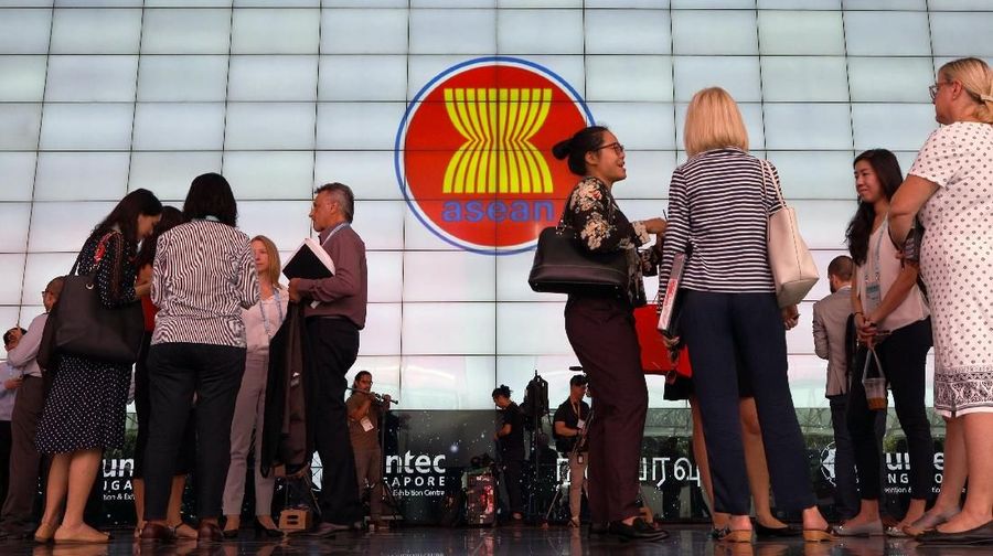 Delegates stand next to the ASEAN Summit signage at Suntec Convention Centre in Singapore, November 12, 2018. REUTERS/Athit Perawongmetha