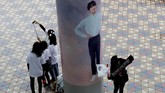 Sejumlah penggemar lain memilih ber-swafoto di depan gambar personel BTS yang ditempel di pilar luar Tokyo Dome. (REUTERS/Kim Kyung-Hoon)