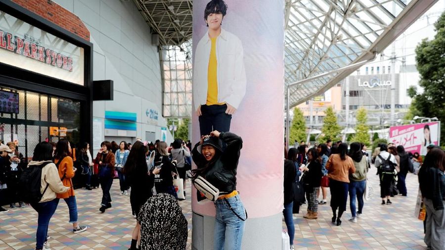 A girl poses in front of a wall photo of a member of South Korean boy band BTS outside Tokyo Dome where the band's concert will be held in Tokyo, Japan, November 13, 2018. REUTERS/Kim Kyung-Hoon