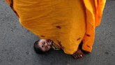 Wanita ini melangkahi seorang bayi mungil, sebuah bagian dari ritual meminta berkat dari Dewa Matahari untuk si bayi di Kolkata, India. (REUTERS/Rupak De Chowdhuri)
