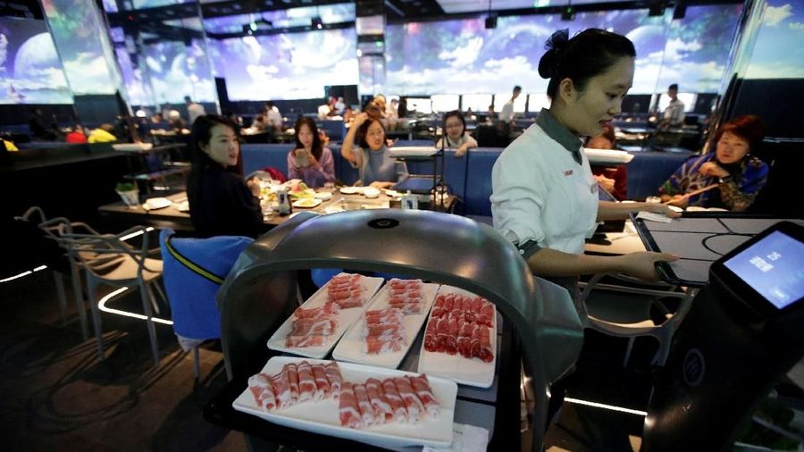 A robot server carrying dishes to fulfill diners' order arrives at a table in Haidilao's new artificial intelligence hotpot restaurant in Beijing, China, November 14, 2018. Picture taken November 14, 2018. REUTERS/Jason Lee TPX IMAGES OF THE DAY