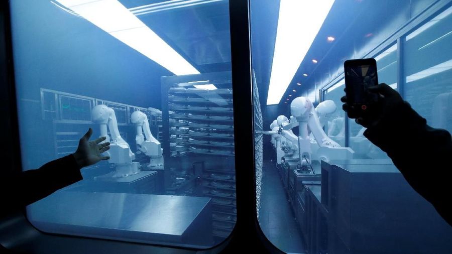 A customer takes a picture as robotic arms collect pre-packaged dishes from a cold storage, done according to the diners' orders, at Haidilao's new artificial intelligence hotpot restaurant in Beijing, China, November 14, 2018. Picture taken November 14, 2018. REUTERS/Jason Lee
