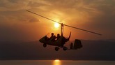 Gyrocopter yang terbang di atas kawasan Laut Mati, Yordania, kala matahari terbenam.