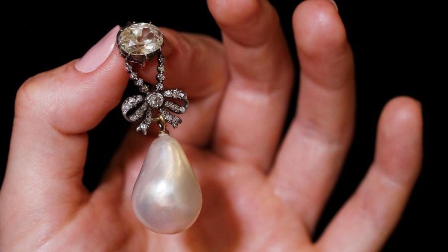 A natural pearl and diamond pendant once owned by Marie Antoinette is held by a model during a press preview ahead of the upcoming auction 