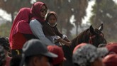 Warga menaiki kudanya saat menyaksikan lomba pacuan kuda tradisional.