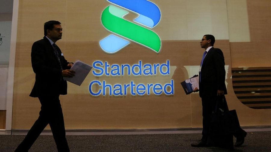 FILE PHOTO: People pass by the logo of Standard Chartered plc at the SIBOS banking and financial conference in Toronto, Ontario, Canada October 19, 2017. REUTERS/Chris Helgren/File Photo
