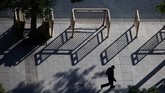 Seorang pria berjalan di Chang'an, Beijing, sementara di sekitarnya terlihat bayangan-bayangan panjang pembatas jalan. (REUTERS/Thomas Peter)