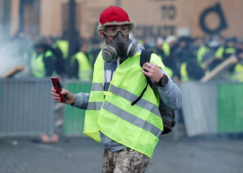 Para pengunjuk rasa mengenakan rompi kuning, simbol protes seorang pengendara Prancis terhadap harga bahan bakar yang lebih tinggi, berdiri di depan sebuah kanon polisi air selama bentrokan di Champs-Elysees di Paris, Prancis, 24 November 2018. REUTERS / Benoit Tessier Protesters wearing yellow vest, a symbol of a French drivers' protest against higher fuel prices, stand up in front of a police water canon during clashes on the Champs-Elysees in Paris, France, November 24, 2018. REUTERS/Benoit Tessier