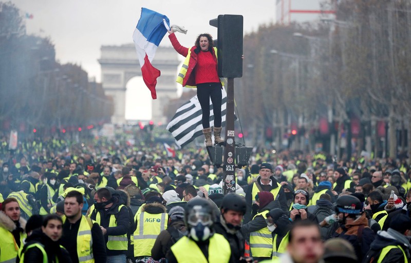Protesters wearing yellow vest, a symbol of a French drivers' protest against higher fuel prices, stand up in front of a police water canon during clashes on the Champs-Elysees in Paris, France, November 24, 2018. REUTERS/Benoit Tessier