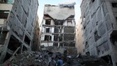 Warga Palestina berdiri di dekat sisa-sisa bangunan yang hancur oleh serangan udara Israel, di Kota Gaza (REUTERS/Suhaib Salem)