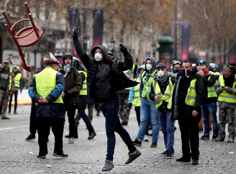 Protesters wearing yellow vest, a symbol of a French drivers' protest against higher fuel prices, stand up in front of a police water canon during clashes on the Champs-Elysees in Paris, France, November 24, 2018. REUTERS/Benoit Tessier