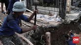 Petugas dari Dinas Sumber Daya Air atau lebih dikenal dengan sebutan pasukan biru mematok tiang pancang agar tak terjadi longsor susulan, Selasa (27/11). (CNN Indonesia/Andry Novelino)
