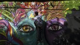 Seorang artis mural mengerjakan gambar mata memandang untuk San Carlos yang lebih baik. (Photo by JOAQUIN SARMIENTO / AFP)
