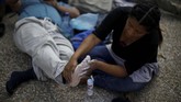 Seorang wanita memijat kaki pasangannya. Keduanya berasal dari El Salvador, dan sedang singgah untuk beristirahat di Guatemala. (REUTERS/Jose Cabezas)