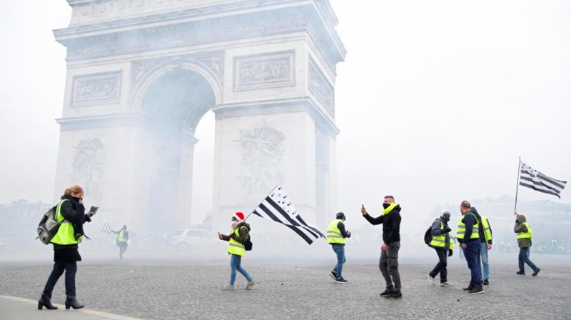 Protesters wearing yellow vest, a symbol of a French drivers' protest against higher fuel prices, stand up in front of a police water canon during clashes on the Champs-Elysees in Paris, France, November 24, 2018. REUTERS/Benoit Tessier