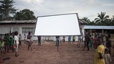 Anak-anak Afrika untuk pertama kalinya dalam hidup melihat layar lebar yang akan digunakan menonton film bersama. Mereka berkerumun dan menunggu dengan tak sabar. (Photo by FLORENT VERGNES / AFP)